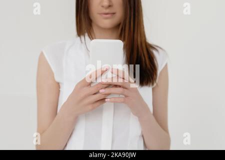 Image rognée d'une belle femme avec un long message écrit sur un smartphone sur fond blanc. Banque D'Images