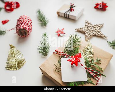 Cadeaux de Noël DIY emballés dans du papier artisanal avec des branches de sapin. Décorations rouges en forme d'arbre de Noël. Cadeaux de la nouvelle année. Fond festif. Banque D'Images