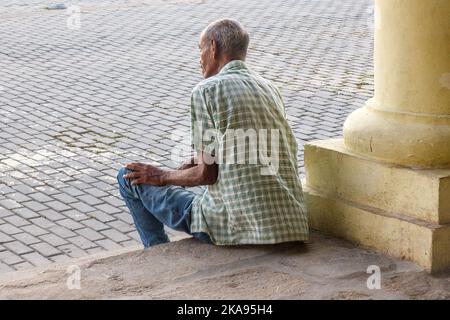 Un homme cubain de haut niveau est assis sur un porche de la Plaza Vieja, dans la vieille Havane. Le célèbre endroit manque de touristes traditionnels. Banque D'Images