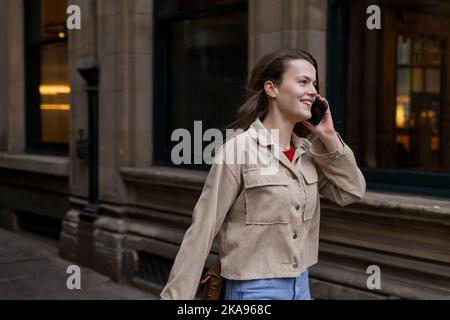 Une jeune femme passant la journée à Newcastle upon Tyne. Elle parle à un ami sur son téléphone mobile pendant qu'elle marche à travers la ville. Banque D'Images