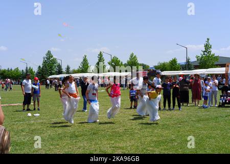 Les gens qui s'amusent à la course de gunnysack sur l'herbe en une journée ensoleillée. Rire, sourire et sauter des gens Banque D'Images