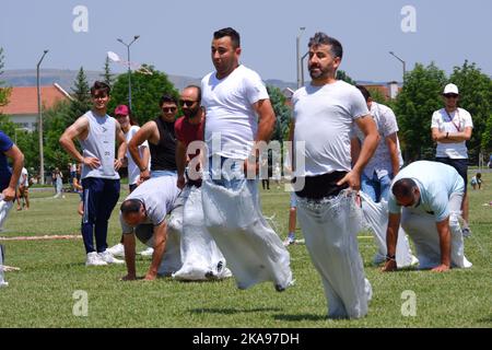 Les gens qui s'amusent à la course de gunnysack sur l'herbe en une journée ensoleillée. Rire, sourire et sauter des gens Banque D'Images