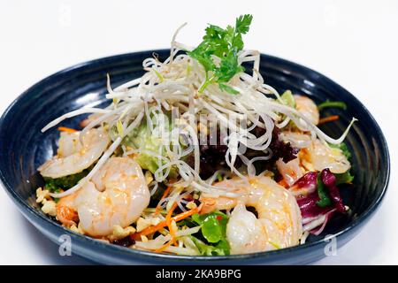 salade de crevettes épicée de style thaïlandais avec légumes croquants, arachides et pousses de haricots sur fond blanc Banque D'Images