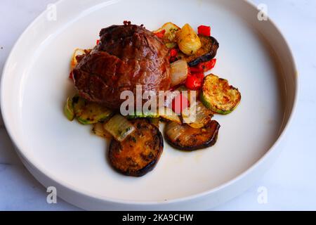 Viande de bœuf grillée avec des légumes dans une assiette blanche sur la table Banque D'Images