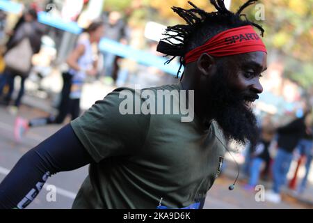 New York City Marathon Runner, homme noir enthousiaste aux cheveux sauvages, bandana Spartan rouge et chemise verte Banque D'Images