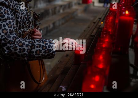 Barcelone - Espagne, 10 avril 2022: Main d'une femme croyant méconnaissable qui éclaire une bougie dans la cathédrale de Barcelone (Espagne). Banque D'Images