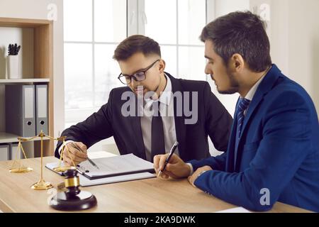 Des collègues sérieux d'avocats étudient ensemble des documents juridiques en lisant des informations sur les affaires judiciaires. Banque D'Images