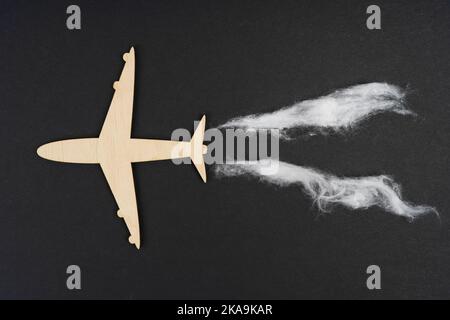 Concept d'écologie et de transport. L'avion vole et laisse derrière lui des traces d'émissions. Isolé sur fond noir. Banque D'Images