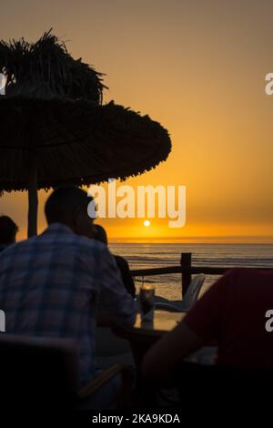 Peu de gens apprécient leur soirée avec une vue sur l'océan au coucher du soleil Banque D'Images