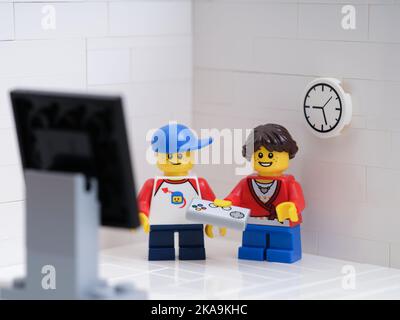 Tambov, Fédération de Russie - 6 septembre 2022 deux figurines Lego pour enfants jouer à un jeu vidéo avec une manette de jeu. Banque D'Images