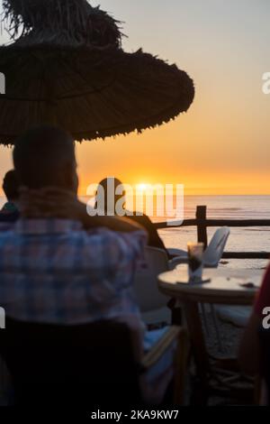 Peu de personnes appréciant leur soirée avec une vue sur l'océan au coucher du soleil Banque D'Images