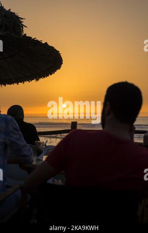 Peu de gens apprécient leur soirée avec une vue sur l'océan au coucher du soleil Banque D'Images