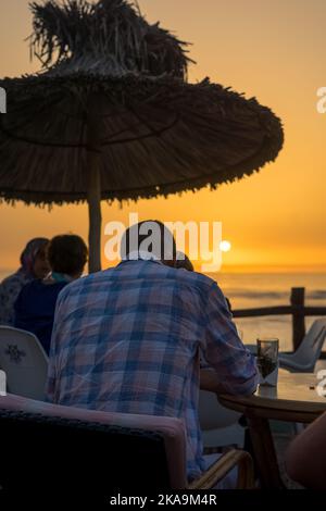 Peu de gens apprécient leur soirée avec une vue sur l'océan au coucher du soleil Banque D'Images