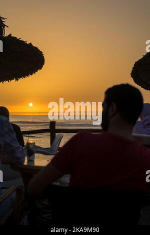 Peu de personnes appréciant leur soirée avec une vue sur l'océan au coucher du soleil Banque D'Images