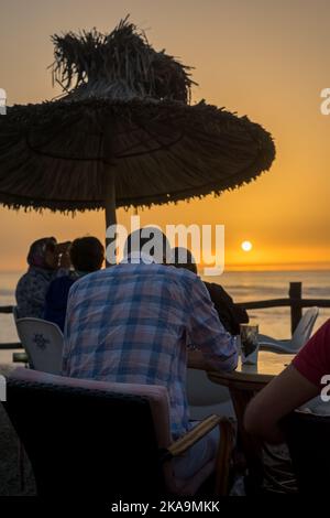 Peu de gens apprécient leur soirée avec une vue sur l'océan au coucher du soleil Banque D'Images