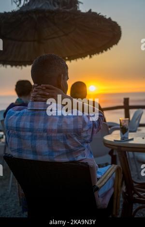 Peu de personnes appréciant leur soirée avec une vue sur l'océan au coucher du soleil Banque D'Images