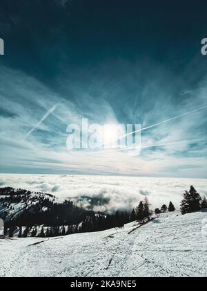 Un cliché vertical du ciel bleu sur les montagnes couvertes de nuages en hiver Banque D'Images