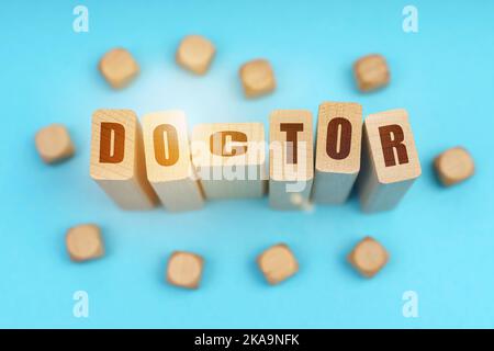 Concept de médecine. Sur fond bleu, cubes en bois et Jenga avec l'inscription - MÉDECIN Banque D'Images