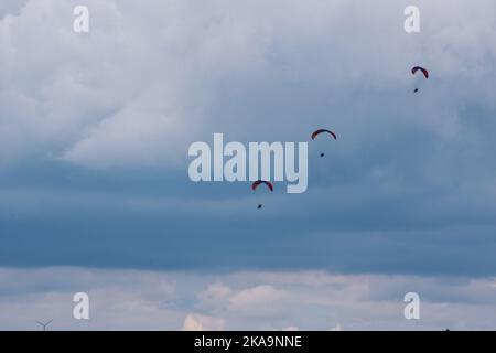 Trois cavaliers en parachute dans un ciel nuageux dans des nuages sombres Banque D'Images