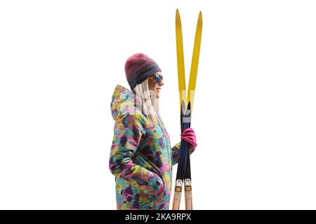 Photo de profil d'une femme dans un pantalon de ski et une veste tenant une paire de skis isolés sur un fond blanc Banque D'Images