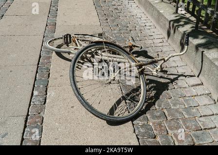 Une vieille bicyclette sale se trouve au milieu de la rue. Banque D'Images