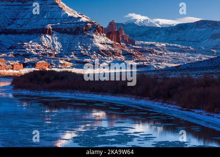 Fisher Towers au-dessus du fleuve Colorado glacé au coucher du soleil en hiver avec les montagnes de la Sal derrière. Près de Moab, Utah. Banque D'Images