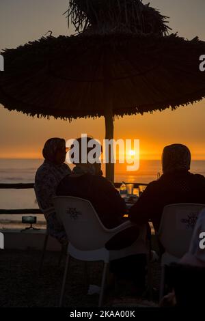 Peu de gens apprécient leur soirée avec une vue sur l'océan au coucher du soleil Banque D'Images