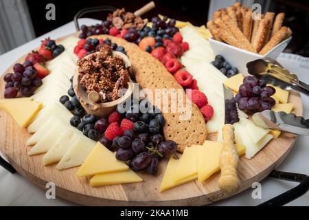 Divers fromages, craquelins, baies et noix sur un tableau de charcuterie fine Banque D'Images