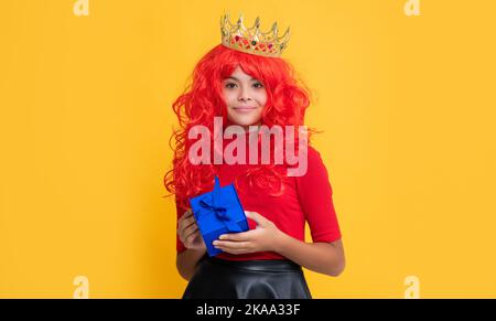 enfant joyeux en tiara avec boîte de cadeau sur fond jaune Banque D'Images