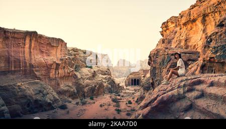 Caucasienne jeune touriste s'asseoir et sourire tout en regardant de belles sculptures de la ville antique de Petra. Visitez la célèbre destination d'attraction Jordan. Pétra Banque D'Images