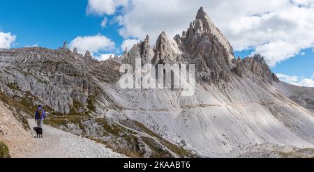 Une femme randonnée solitaire avec son chien autour des montagnes de Drei Zinnen, les Dolomites dans le Tyrol du Sud Banque D'Images