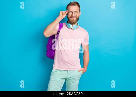 Photo portrait de jeune gars attrayant spécifications intelligents étudiants écouteurs habillés élégant rose look isolé sur fond bleu-vert couleur Banque D'Images