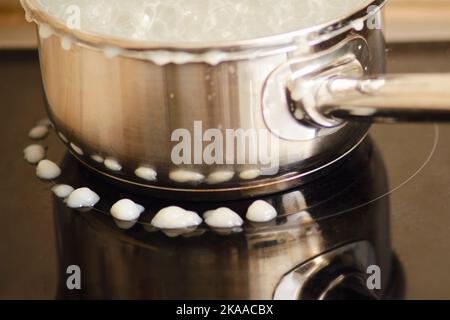 Porridge de lait versé pendant l'ébullition de sous le couvercle de la casserole sur un poêle à induction électrique Banque D'Images