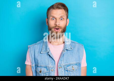 Photo d'un jeune garçon impressionné choqué vêtu denim gilet grands yeux isolé couleur bleu fond Banque D'Images