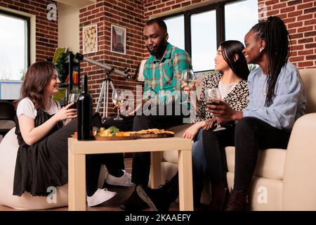 Groupe de personnes multiculturelles ayant heureux, agréable chat, conversation, boire du vin, rire, s'amuser les uns les autres. Des amis de différentes nationalités se sont réunis, parlant à la fête des collations. Banque D'Images