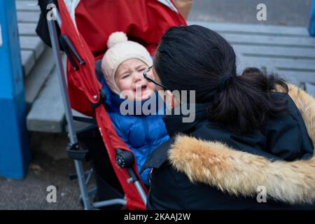Maman sur le terrain de jeu avec un enfant en pleurs dans la poussette Banque D'Images