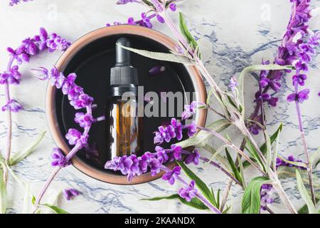 Vue de dessus de la bouteille d'huile essentielle entourée de feuilles et de fleurs de lavande Banque D'Images
