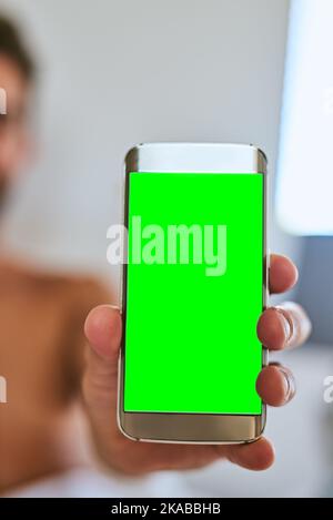 L'écran sur lequel vous pouvez mettre n'importe quoi. Un homme méconnaissable tenant un téléphone portable avec un écran vert à la maison. Banque D'Images