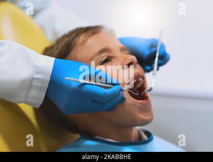 Tout semble en place. Un jeune petit garçon allongé sur une chaise de dentiste tout en obtenant un contrôle du dentiste. Banque D'Images