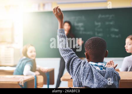 Oui, vous dans le dos. Les enfants de l'école primaire élèvent leurs mains pour poser des questions dans la classe. Banque D'Images