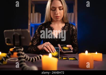 Une femme au paller de fortune lit des cartes de tarot pour des prédictions, en disant aux clients en fournissant des services via webcam de téléphones mobiles, nouveau concept de service. Banque D'Images