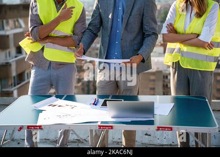 Équipe diversifiée de spécialistes avec ordinateur sur le chantier de construction. Projet de construction avec des ingénieurs Banque D'Images