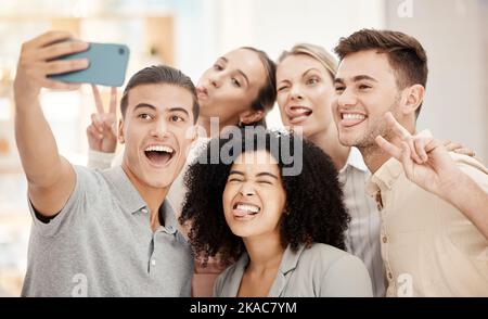 Téléphone, selfie et collègues de travail avec des visages drôles lors d'un événement de renforcement d'équipe ou d'une réunion au bureau. Comique, diversité et goofy les gens d'affaires dans Banque D'Images