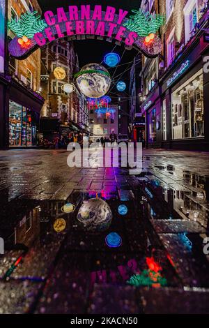 Réflexions après la pluie des lumières de Noël de Carnaby 2022 Banque D'Images