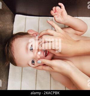 Une mère nettoie son nez avec un coton-tige à un bébé garçon heureux. Maman nettoie les narines d'un enfant souriant. Enfant d'un an Banque D'Images