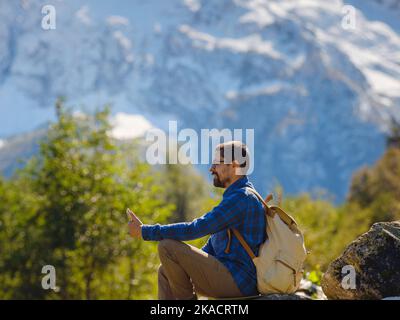 Voyage par la vallée d'Irkis, Arkhyz, Karachay-Cherkessia, Nord Caucase. Homme randonnée en montagne dans la vallée de montagne enneigée avec ciel bleu et nuages et belle forêt près de la rivière Psysh, Caucase. Banque D'Images