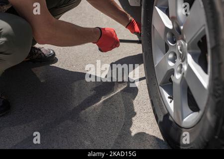 MINSK, BÉLARUS - octobre 17 2021 mains mettant des cales de roue sous les pneus de voiture sur la route. Banque D'Images