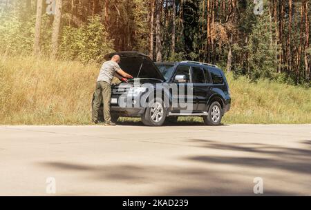 MINSK, BÉLARUS - octobre 17 2021 Homme conducteur debout près de la voiture avec le capot levé et de vérifier les problèmes. Banque D'Images