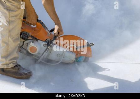 Scie à lame de diamant utilisée par le travailleur de la construction pour couper le trottoir en béton dans les travaux de réconciliation Banque D'Images