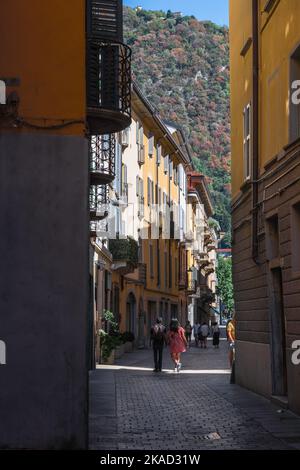 Voyage en couple, vue arrière en été d'un couple de touristes explorant une rue étroite dans le centre historique de la ville de Côme, Lombardie, Italie, Europe Banque D'Images